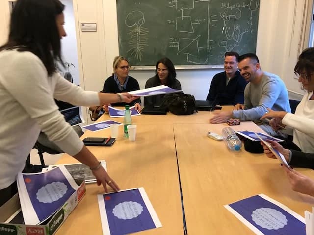 Groupe de participants à la formation : distribution de documents et supports pédagogiques en salle.